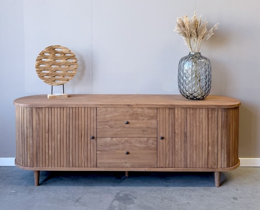 tv-meubel-oval-200cm-breed-massief-teakhout-indoteak-7 Ovaal tv meubel 200 cm van teakhout gestyled met vaas en decoratie op het blad