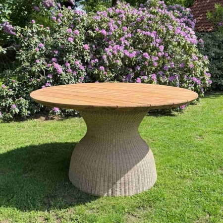 Ronde Ubud tuintafel van massief teakhout met wicker onderstel in groene tuin