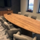Maatwerk ovale teakhouten vergadertafel met bijpassend dressoir in een moderne boardroom met uitzicht op het water